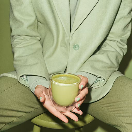 Person der holder en kop matcha