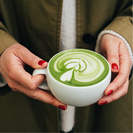 Person der holder en kop matcha